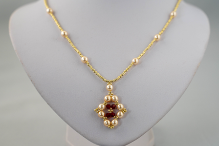 Pearl & Ruby Blossom – Goudkleurige Ketting met Parel en Ruby Accenten